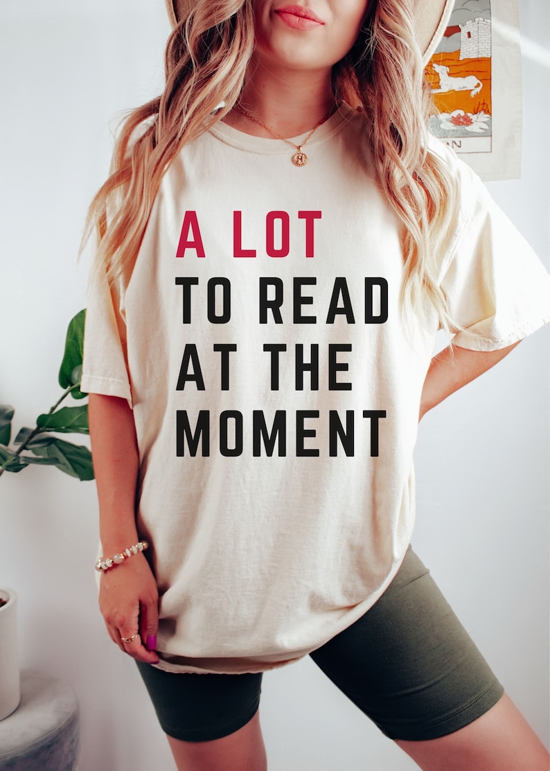 May include: A white t-shirt with the text "A LOT TO READ AT THE MOMENT" printed in black and red.