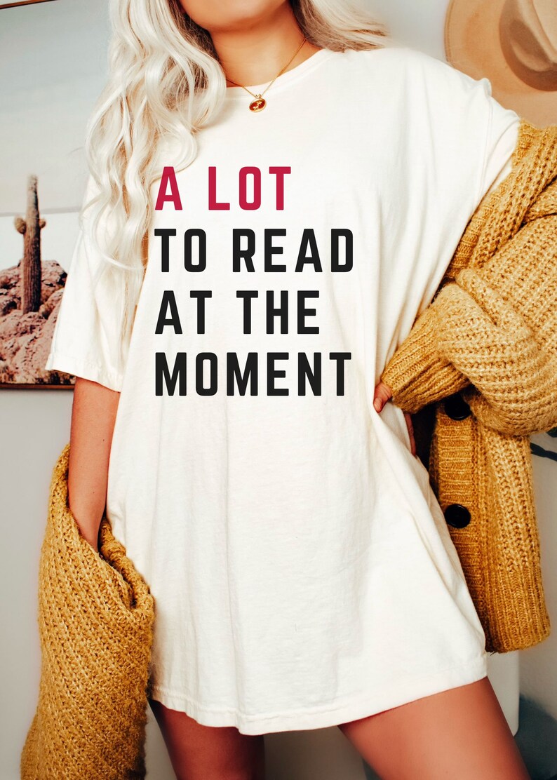 May include: A white t-shirt with the text "A LOT TO READ AT THE MOMENT" printed in black with the word "LOT" in red.