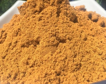 May include: A close-up of a pile of ground turmeric powder. The powder is a vibrant yellow-orange color and has a fine, granular texture.