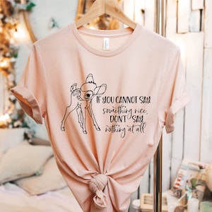 May include: A light pink t-shirt with a black outline of a fawn and the text "If you cannot say something nice, don't say nothing at all".