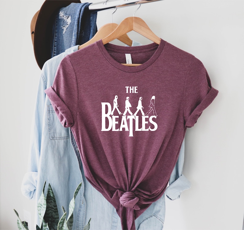 May include: A maroon t-shirt with a white graphic of the Beatles walking across the street, with the text "THE BEATLES" underneath.