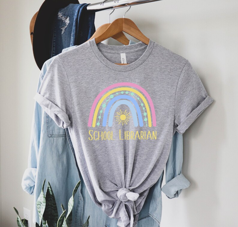 May include: A gray t-shirt with a rainbow and sun graphic and the text "SCHOOL LIBRARIAN" in yellow.