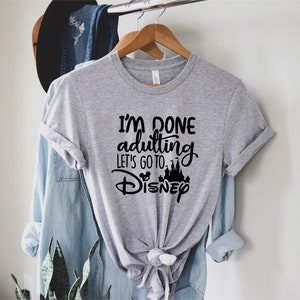 May include: Gray t-shirt with black text that reads "I'm done adulting let's go to Disney" with a black silhouette of Cinderella's castle and Mickey Mouse ears.