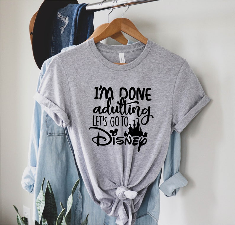 May include: Gray t-shirt with black text that reads "I'm done adulting let's go to Disney" with a black silhouette of Cinderella's castle and Mickey Mouse ears.