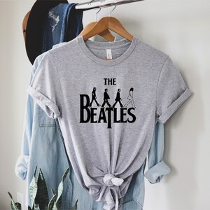 May include: A gray t-shirt with a black graphic of the Beatles walking across a crosswalk with the text "THE BEATLES" underneath.