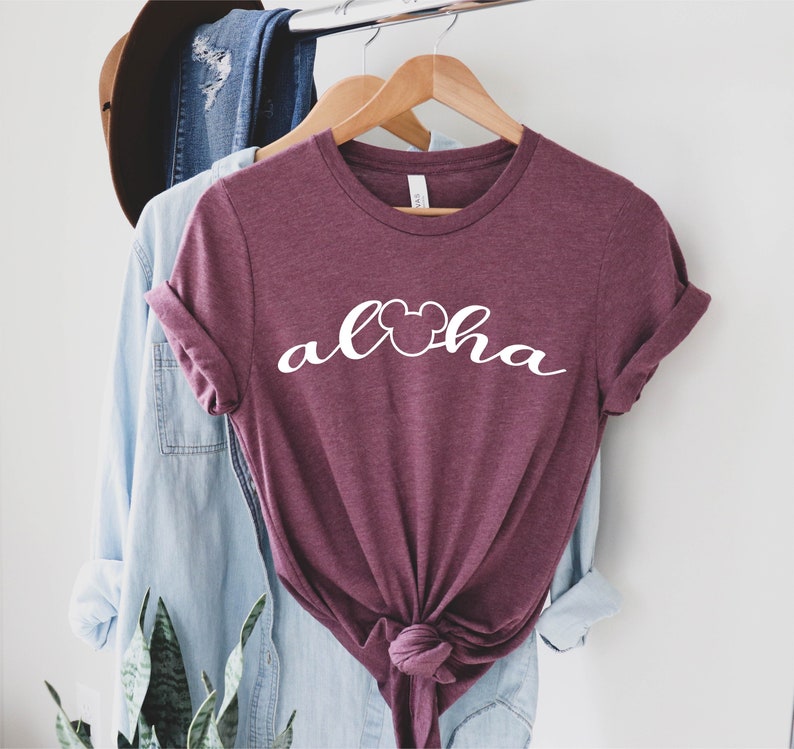 May include: A maroon t-shirt with white text that says "Aloha" with a Mickey Mouse head in the "o".