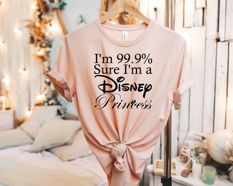 May include: A light pink t-shirt with the text "I'm 99.9% Sure I'm a Disney Princess" printed in black.