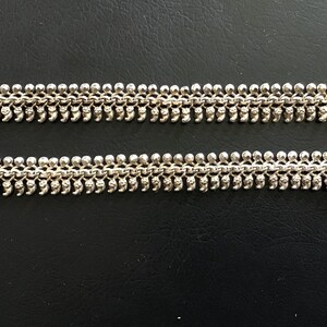 Peut inclure: Un bracelet de cheville en argent avec une chaîne délicate et des breloques en forme de larme. Le bracelet de cheville est composé de plusieurs rangées de petits maillons reliés.