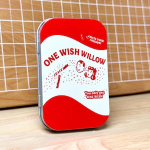 May include: A rectangular tin with a red and white design. The tin reads "ONE WISH WILLOW" with illustrations of a firecracker, a man, and a woman. The text "AMAZE YOUR FRIENDS!" and "You only get ONE WISH" are also visible.