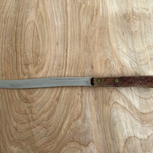 May include: A stainless steel knife with a wooden handle. The blade is marked "FLAT STAINLESS" and "JAPAN" on the side.