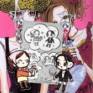 Pode incluir: Um chaveiro com dois personagens em estilo anime segurando uma faixa cinza com ilustrações de desenhos animados. A faixa tem o texto "ZEYNEP'S CINEMA CLUB". O fundo é uma ilustração rosa e vermelha.