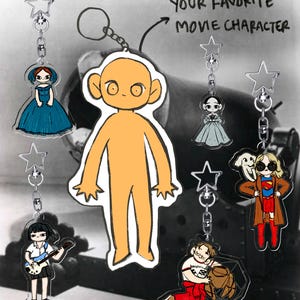 Könnte beinhalten: Eine Sammlung von Acryl-Schlüsselanhängern mit verschiedenen illustrierten Figuren, darunter eine große orangefarbene Gestalt, eine Person in einem blauen Kleid, eine Person mit Gitarre und eine Person im Superheldenkostüm. Der Text lautet YOUR FAVORITE MOVIE CHARACTER.
