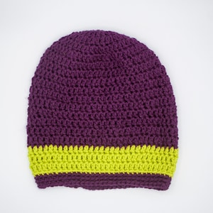 Puede incluir: Gorro de punto de color morado con una franja amarilla alrededor de la parte inferior.