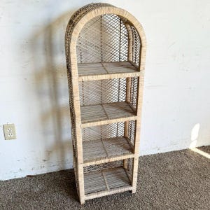 May include: A white wicker shelf unit with an arched top and four shelves. The shelf unit is made of woven wicker and has a natural finish.
