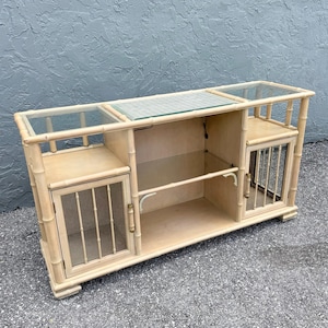 May include: A light-colored bamboo-style cabinet with glass shelves and door panels. The cabinet has a rectangular shape with multiple compartments and a lower shelf. The glass panels are clear, and the bamboo-style frame has a natural finish.