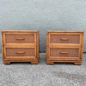 May include: Two matching bamboo nightstands with two drawers each. The drawers have woven rattan panels and wooden handles. The nightstands are a warm brown color and sit on a decorative base.