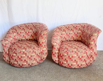 May include: Two matching armchairs with a rounded design. The chairs are upholstered in a red, beige, and cream geometric pattern. The chairs have a low profile and curved arms, suitable for a living room or lounge area.