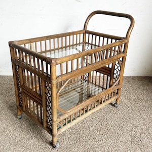 May include: A two-tiered bamboo serving cart with glass shelves and wheels. The cart is made of natural brown bamboo and has a simple, elegant design.