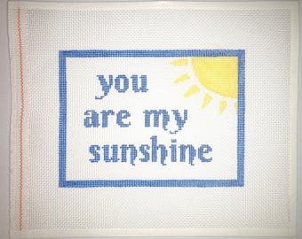 May include: A white canvas with a blue frame and a yellow sun graphic. The text "you are my sunshine" is written in blue letters inside the frame.