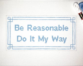May include: A white canvas with a blue border and the text "Be Reasonable Do It My Way" in blue lettering.