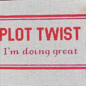 May include: A white needlepoint canvas featuring a red rectangular border and the red text "PLOT TWIST" in a bold sans-serif font, followed by the smaller pink text "I'm doing great" in a serif font, with three skeins of embroidery thread in the corner.