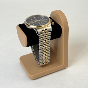 May include: A gold and silver watch with a black face and a brown watch stand.