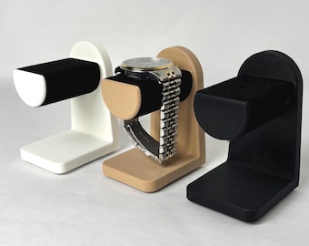 May include: Three watch winders in white, beige, and black. Each winder has a velvet cushion to hold a watch and a base to support the winder.