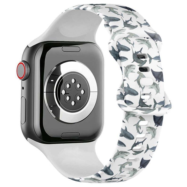 May include: White silicone Apple Watch band with a shark pattern. The band is compatible with Apple Watch Series 4 and later.
