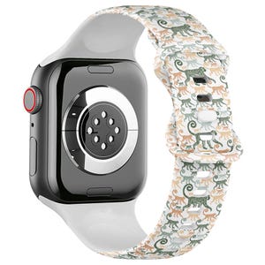 May include: A black smartwatch with a white band featuring a repeating pattern of monkeys in green, tan, and gray. The watch has a red button and a black screen.