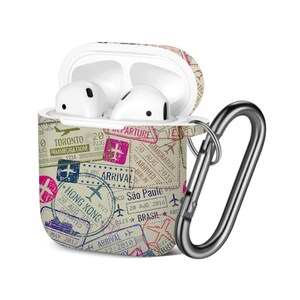 Può includere: Auricolari wireless bianchi in una custodia a tema viaggio con un moschettone argentato. La custodia è beige con timbri colorati di varie città, tra cui Toronto, Hong Kong e San Paolo. La custodia è aperta, rivelando gli auricolari.