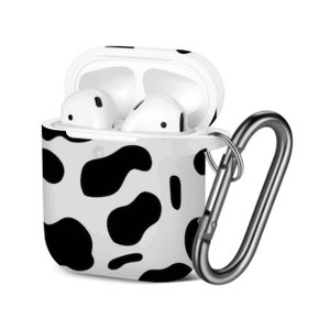 May include: A white and black cow print protective case for AirPods with a silver carabiner clip.