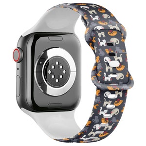 Może przedstawiać: Biały pasek do Apple Watch z kolorowym nadrukiem kotów. Pasek jest wykonany z silikonu i ma zapięcie na klamrę.
