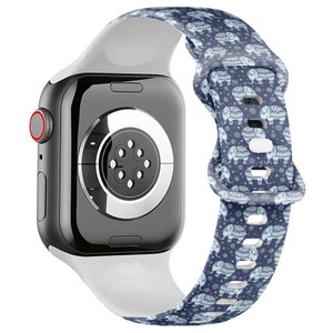 May include: A white and blue patterned silicone watch strap with a white silicone band and a black Apple Watch.