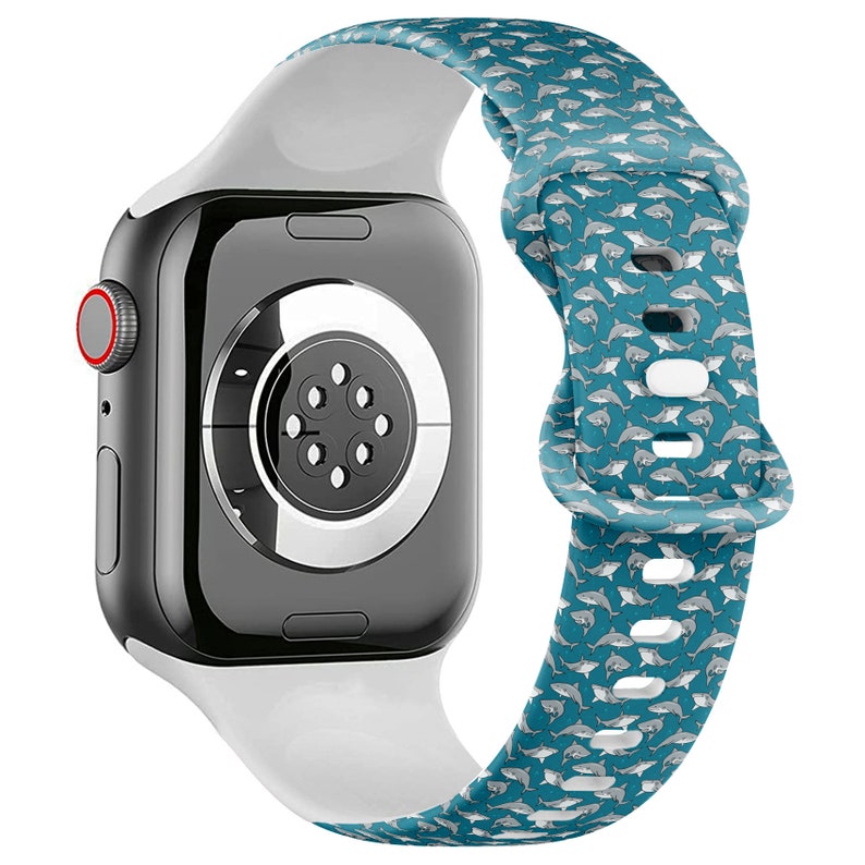 May include: White Apple Watch band with a blue and white shark pattern. The band is made of silicone and has a white buckle.