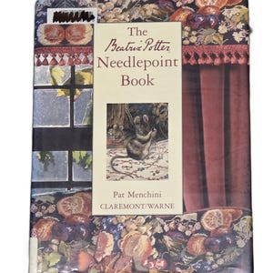 May include: A hardback book titled The Beatrix Potter Needlepoint Book by Pat Menchini. The cover features a central illustration of a mouse sewing, surrounded by a border of floral and fruit patterns, a window view, and deep red curtains.