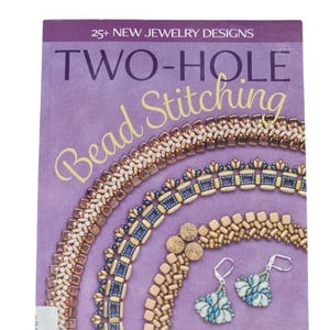 May include: A softcover book titled Two-Hole Bead Stitching by Virginia Jensen with a purple cover. The cover features 25+ New Jewelry Designs text, images of three beaded necklaces in metallic and blue tones, and a pair of matching earrings.