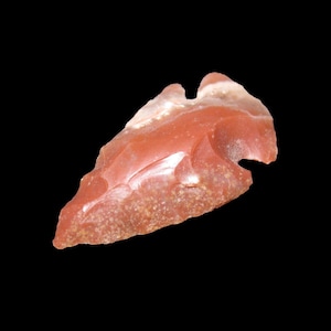 以下が含まれることがあります： 赤と白の石製の矢じり。矢じりは約5センチの長さで、先端が鋭利です。