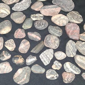 Könnte beinhalten: Ein Set aus drei Keramikbechern mit gesprenkelter, matter Oberfläche. Die Becher sind in Creme-, Hellgrau- und Dunkelgrautönen gehalten. Jeder Becher hat ein schlichtes, minimalistisches Design, ideal für Kaffee oder Tee.