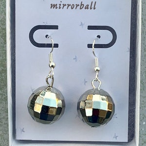 May include: A pair of silver mirrorball earrings in a white box with the word "mirrorball" printed on the card.
