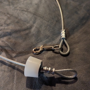 May include: A silver cable with a white plastic end cap and a silver hook. The cable is looped and secured with a silver clasp.