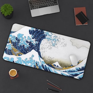 Puede incluir: Una alfombrilla de ratón azul y blanca con un diseño de olas japonesas, un barco dorado y un ratón blanco encima.