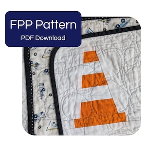 Pode incluir: Uma peça de tecido acolchoado com um design de cone de trânsito laranja e branco com uma borda preta. O tecido tem um fundo branco com uma pequena estampa de veículos de construção. Uma sobreposição azul escura exibe o texto FPP Pattern PDF Download.
