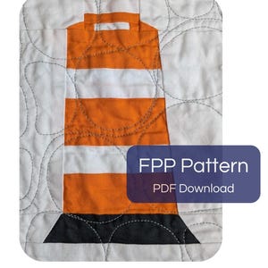 Pode incluir: Um bloco de colcha de tecido com um design de cone de trânsito com listras horizontais laranja e brancas e uma base preta. O tecido de fundo branco tem costuras decorativas curvas. Uma sobreposição roxa exibe o texto FPP Pattern PDF Download.