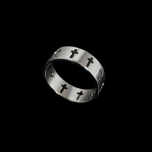 May include: A silver ring with a band of small crosses cut out around the entire ring.