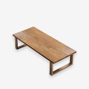 May include: A rectangular wooden coffee table with a light brown finish. The table has a simple design with a flat top and four rectangular legs. The table is approximately 48 inches long and 24 inches wide.