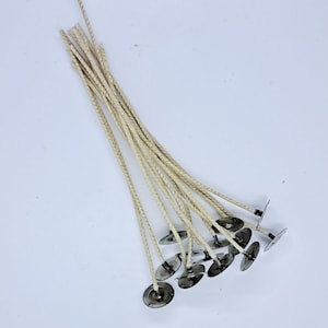 May include: A bundle of 12 natural cotton candle wicks with metal tabs. The wicks are braided and have a natural beige color.
