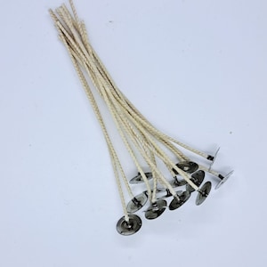 May include: A bundle of 15 natural cotton candle wicks with metal tabs. The wicks are braided and have a natural beige color.