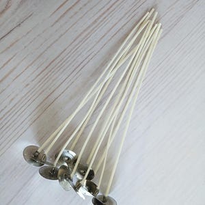 May include: A bundle of white candle wicks with metal bases. The wicks are about 6 inches long and are arranged in a fan shape.