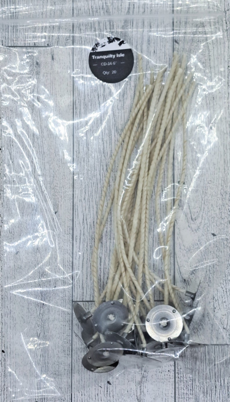 Op de afbeelding: Een doorzichtige plastic zak met 20 witte kaars lonten met metalen bases. De zak heeft een label met de tekst "Tranquility Isle - CD-16 G - Qty. 20".