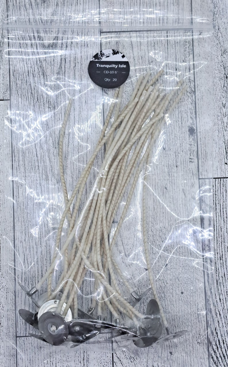 Op de afbeelding: Een verpakking met 20 witte kaars lonten met metalen bases. De verpakking is gelabeld met "Tranquility Isle" en de productcode "CD-106".